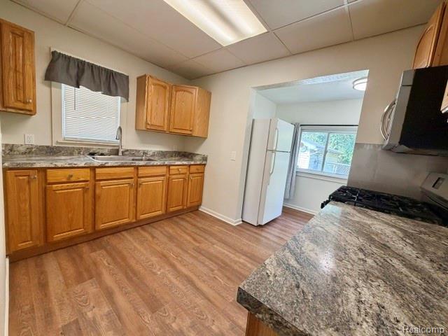 2840 Miller Road Flint, MI 48503 - Photo 12 of 49 Kitchen featuring wood-finish flooring, wood cabinetry, stone-finish countertops, and a stainless steel sink with a gooseneck faucet