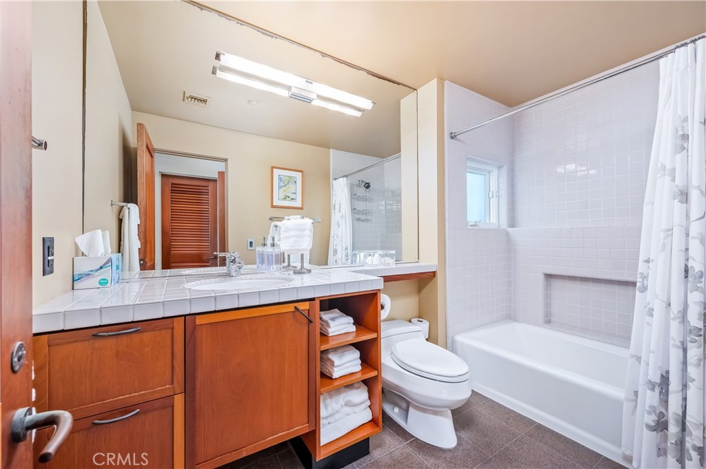 35121 Beach Road Dana Point, CA 92624 - Photo 44 of 46 a bathroom with a granite countertop sink toilet a large mirror a bathtub and shower
