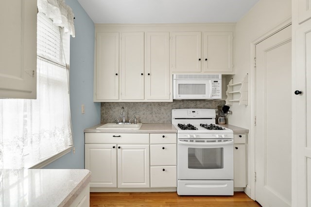 46 Browne Street, Unit 1 Brookline, MA 02446 - Photo 7 of 15 a kitchen with white cabinets and white appliances