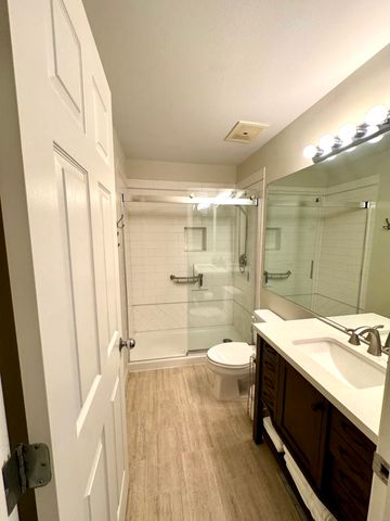 a bathroom with a granite countertop sink a toilet a mirror and shower