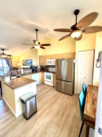 a living room with stainless steel appliances kitchen island granite countertop a table chairs and a refrigerator