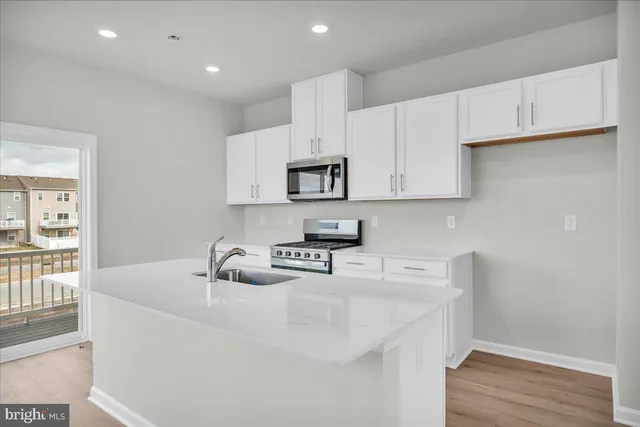 a kitchen with white cabinets and wooden floor