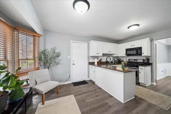 a kitchen with stainless steel appliances granite countertop a refrigerator a stove a sink dishwasher and white cabinets with wooden floor