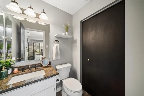 a bathroom with a granite countertop sink mirror vanity and toilet