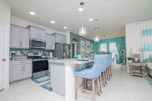 a kitchen with microwave a refrigerator and chairs