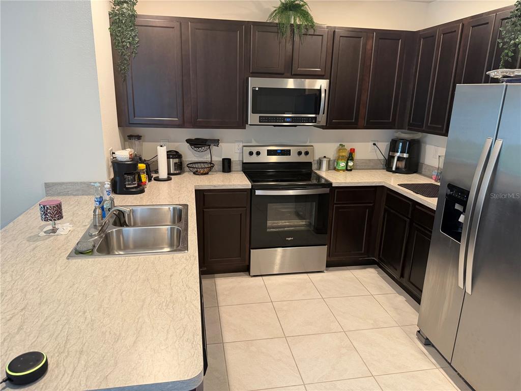 6772 Huntleigh Hammock Road St. Cloud, FL 34773 - Photo 3 of 14 a kitchen with stainless steel appliances a stove a sink a microwave and refrigerator