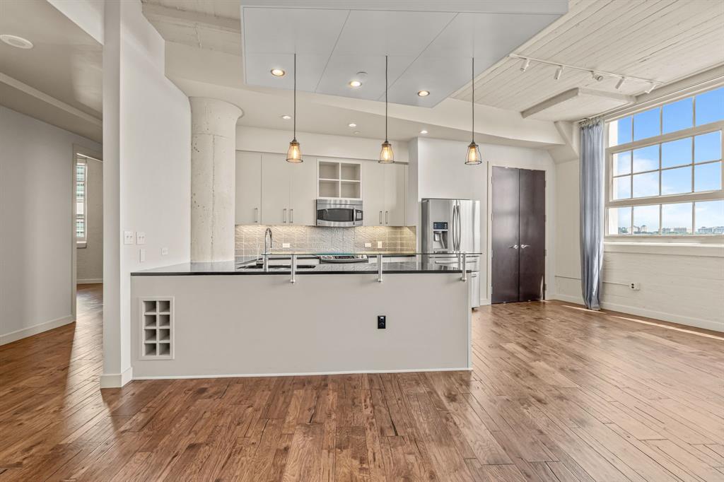 a view of kitchen with granite countertop stainless steel appliances refrigerator wooden floor and cabinets