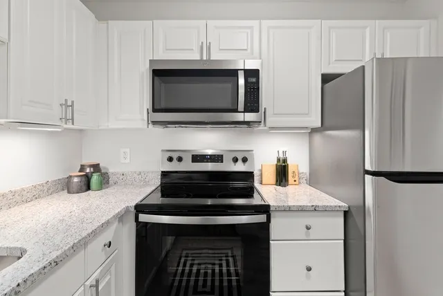 a kitchen with stainless steel appliances granite countertop white cabinets and a stove a oven with white countertops