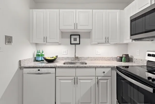 a kitchen with granite countertop white cabinets and white appliances
