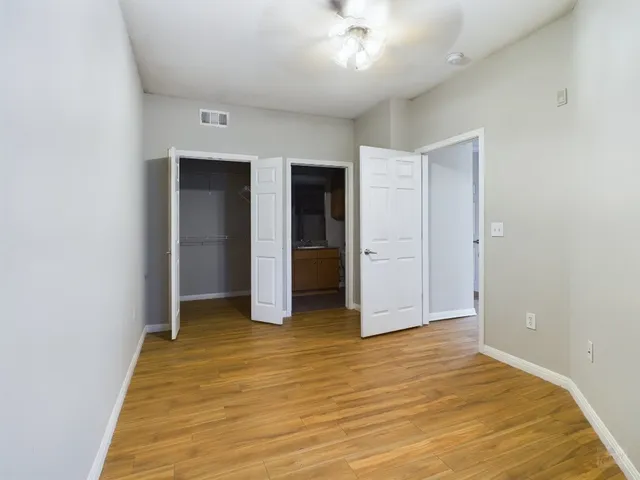 an empty room with closet and a ceiling fan