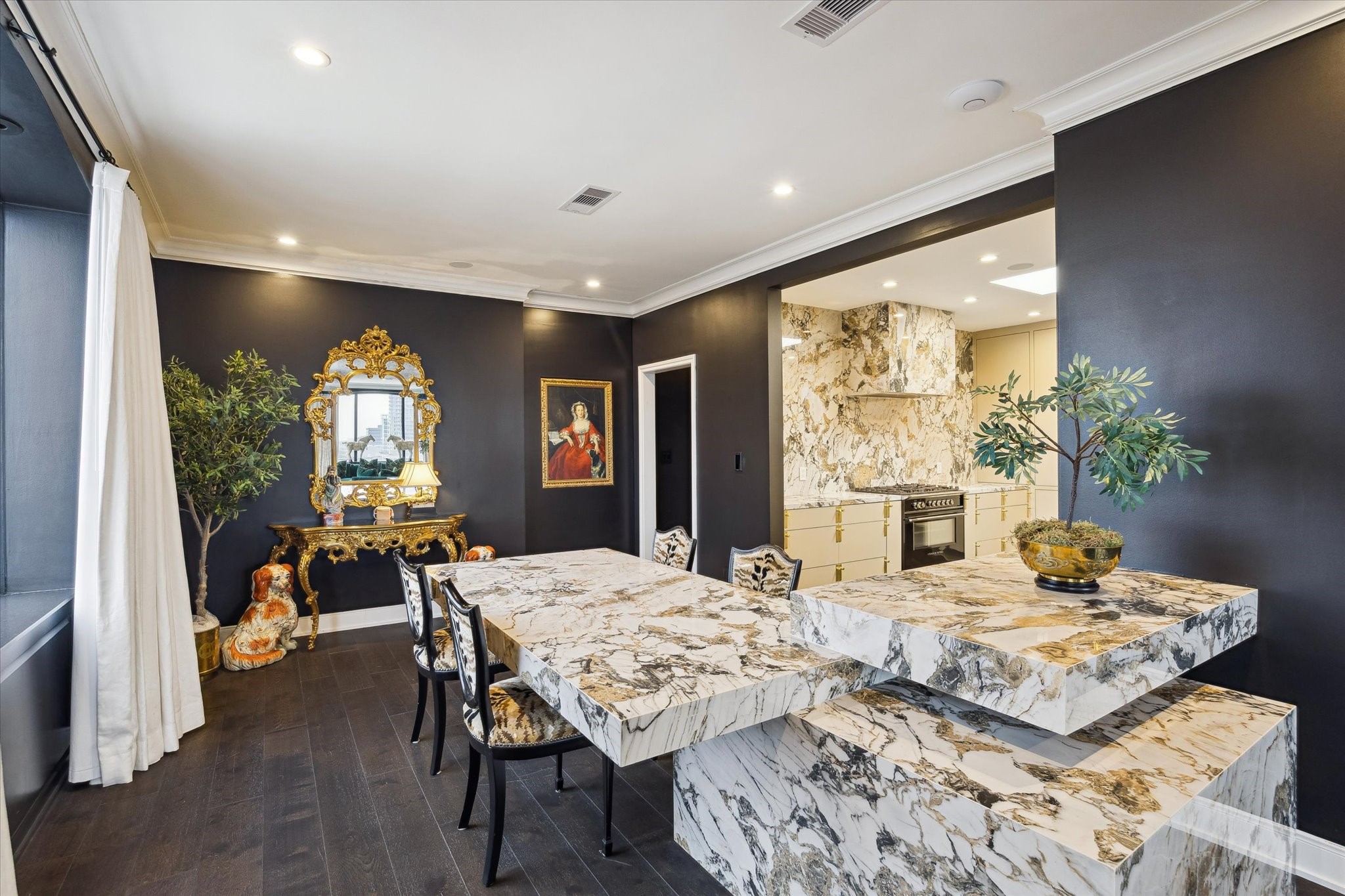 2701 Westheimer Road, Unit PHW Houston, TX 77098 - Photo 8 of 40 The image displays a luxurious, open-concept interior space that combines a dining area, a kitchen/bar space, and a living room. The design features a high-contrast color palette utilizing dark hardwood floors, matte black or very dark gray accent walls, and bright white ceilings with crown molding.