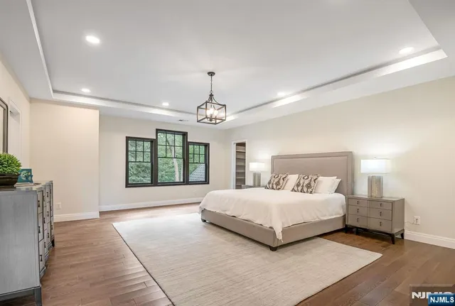 a spacious bedroom with a large bed chandelier and a window