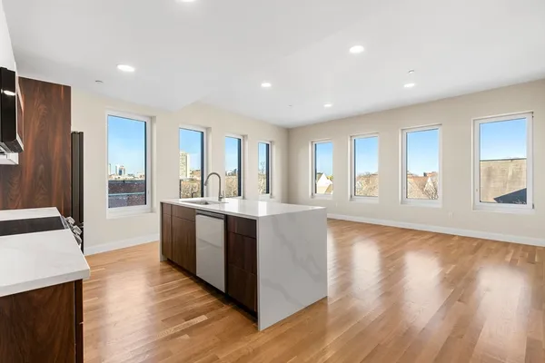 a large kitchen with stainless steel appliances granite countertop a large counter top a wooden floor and large windows