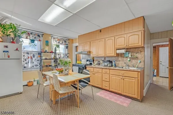 a kitchen with stainless steel appliances granite countertop a refrigerator a sink dishwasher a dining table and chairs with wooden floor