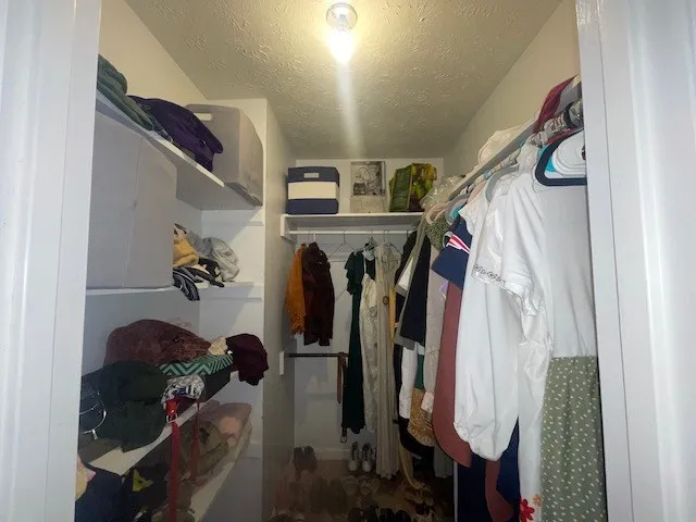 a view of walk in closet with clothes and shoes