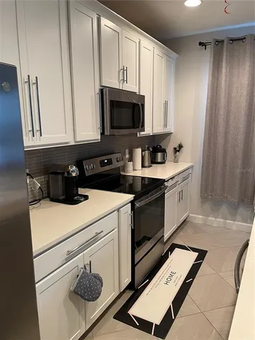 a kitchen with stainless steel appliances a stove a microwave and white cabinets