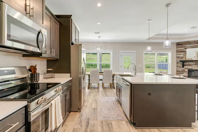 a kitchen with stainless steel appliances granite countertop a stove a sink and a microwave