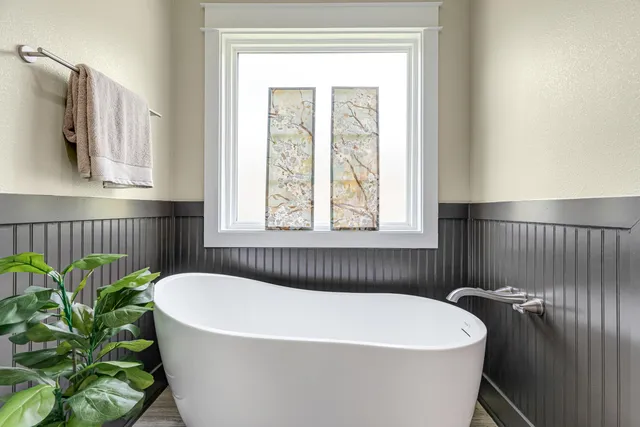 a white bath tub sitting in a bathroom next to a window