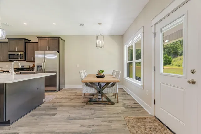 a kitchen with stainless steel appliances granite countertop a refrigerator a sink dishwasher a stove and white cabinets with wooden floor