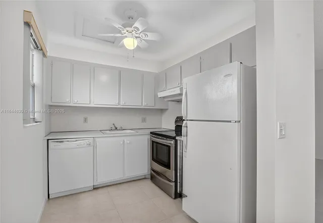 a kitchen with white cabinets and appliances