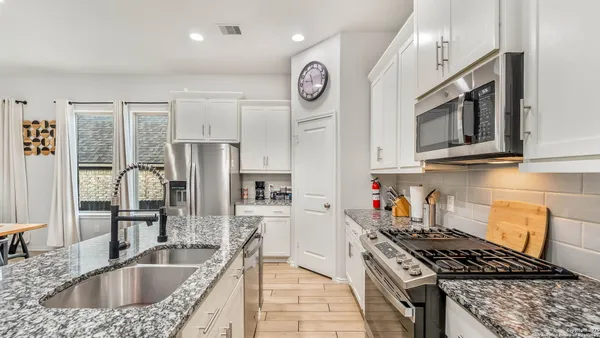 a kitchen with stainless steel appliances granite countertop a sink stove refrigerator and cabinets