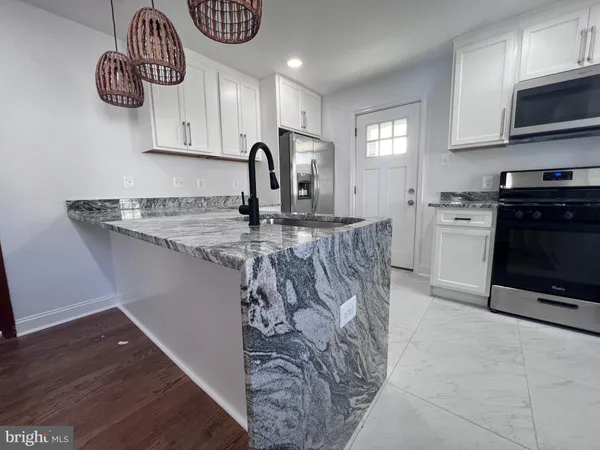 a kitchen with granite countertop a stove a sink and a microwave