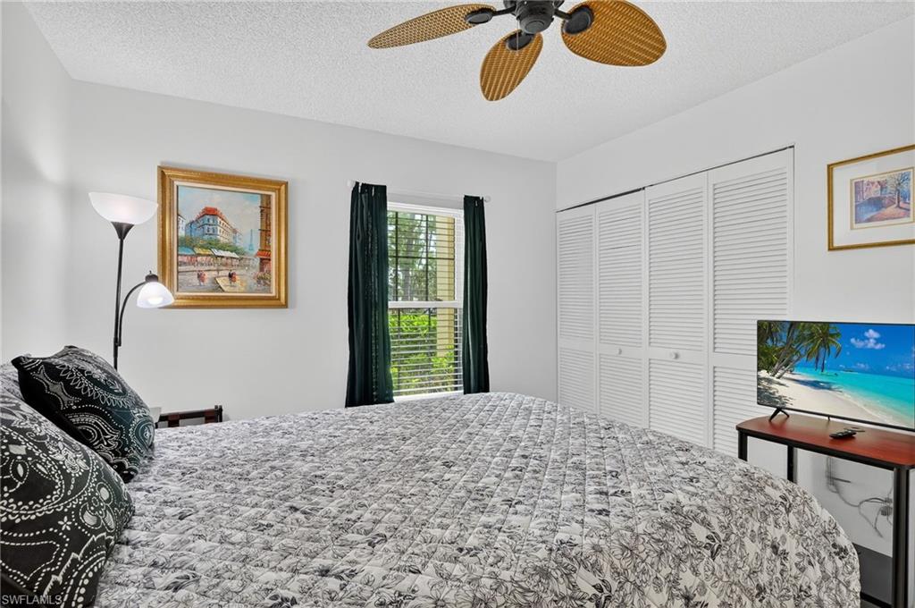 705 Augusta Boulevard, Unit 7054 Naples, FL 34113 - Photo 19 of 28 a bedroom with a bed and a chandelier