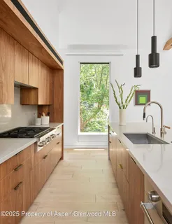 a kitchen with stainless steel appliances granite countertop a sink a stove and a wooden floors