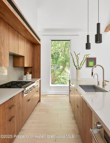 a kitchen with stainless steel appliances granite countertop a sink a stove and a wooden floors