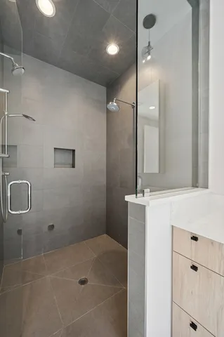 a bathroom with a granite countertop sink a mirror and shower