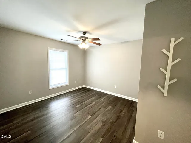 an empty room with wooden floor fan and windows