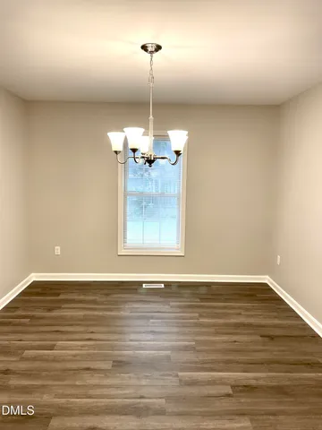 a view of a room with wooden floor kitchen view and a fireplace