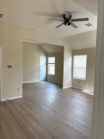 a view of an empty room with a window and wooden floor