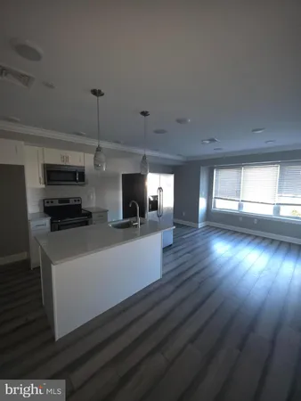 a kitchen with stainless steel appliances a refrigerator a sink a stove a microwave and wooden floor