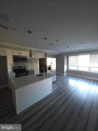 a kitchen with stainless steel appliances a wooden floor stove top oven and cabinets