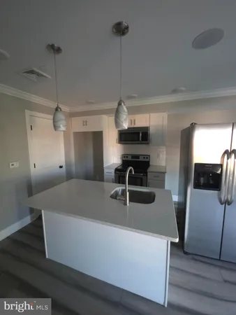 a kitchen with sink a refrigerator and chairs
