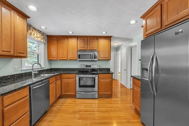 a large kitchen with stainless steel appliances granite countertop a stove a sink dishwasher and a refrigerator