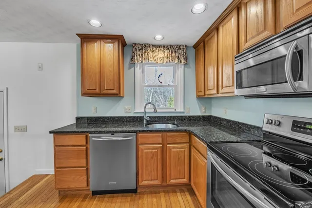 a kitchen with granite countertop a stove a sink and a microwave