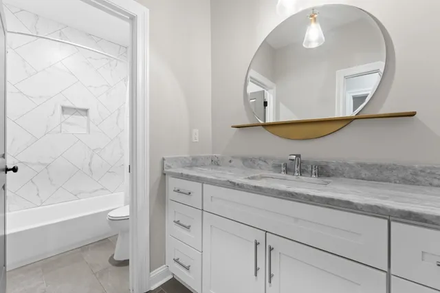 a bathroom with a granite countertop sink a mirror and a bathtub