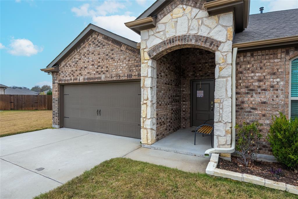 4009 Forest Bend Road Denton, TX 76208 - Photo 3 of 35 View of front of home with brick siding, an attached garage, driveway, stone siding, and a shingled roof
