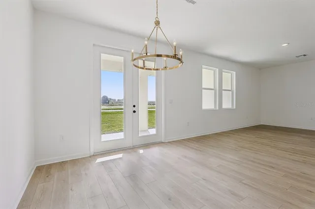 an empty room with wooden floor windows and ceiling fan