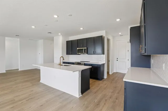 a large kitchen with stainless steel appliances a large counter top a stove and a refrigerator