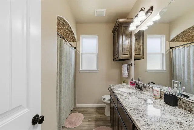 a bathroom with a granite countertop sink a toilet and mirror