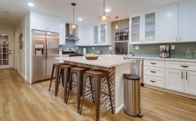 a kitchen with stainless steel appliances granite countertop a table chairs refrigerator and sink