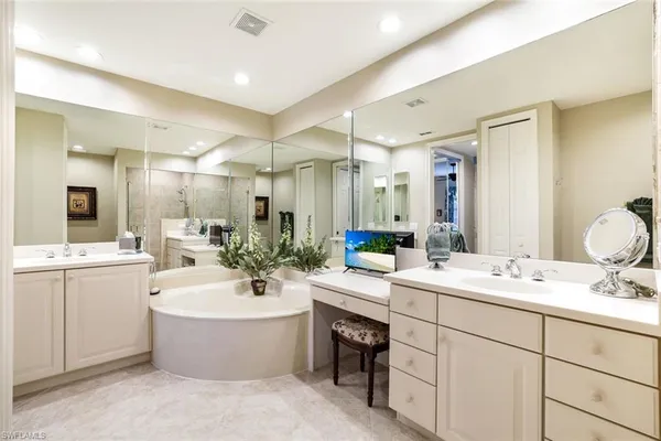 a bathroom with a double vanity sink mirror and bathtub