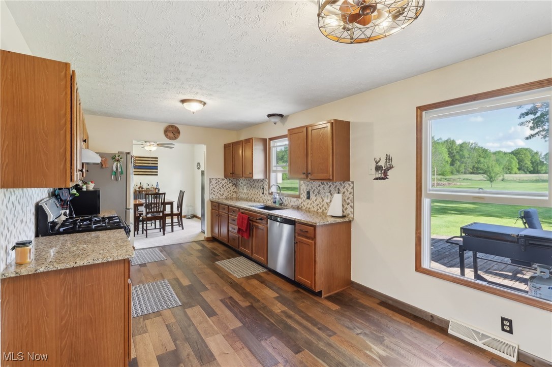 41553 Parsons Road Lagrange, OH 44050 - Photo 24 of 50 Kitchen with dishwasher, a sink, brown cabinetry, dark wood-style flooring, and a textured ceiling