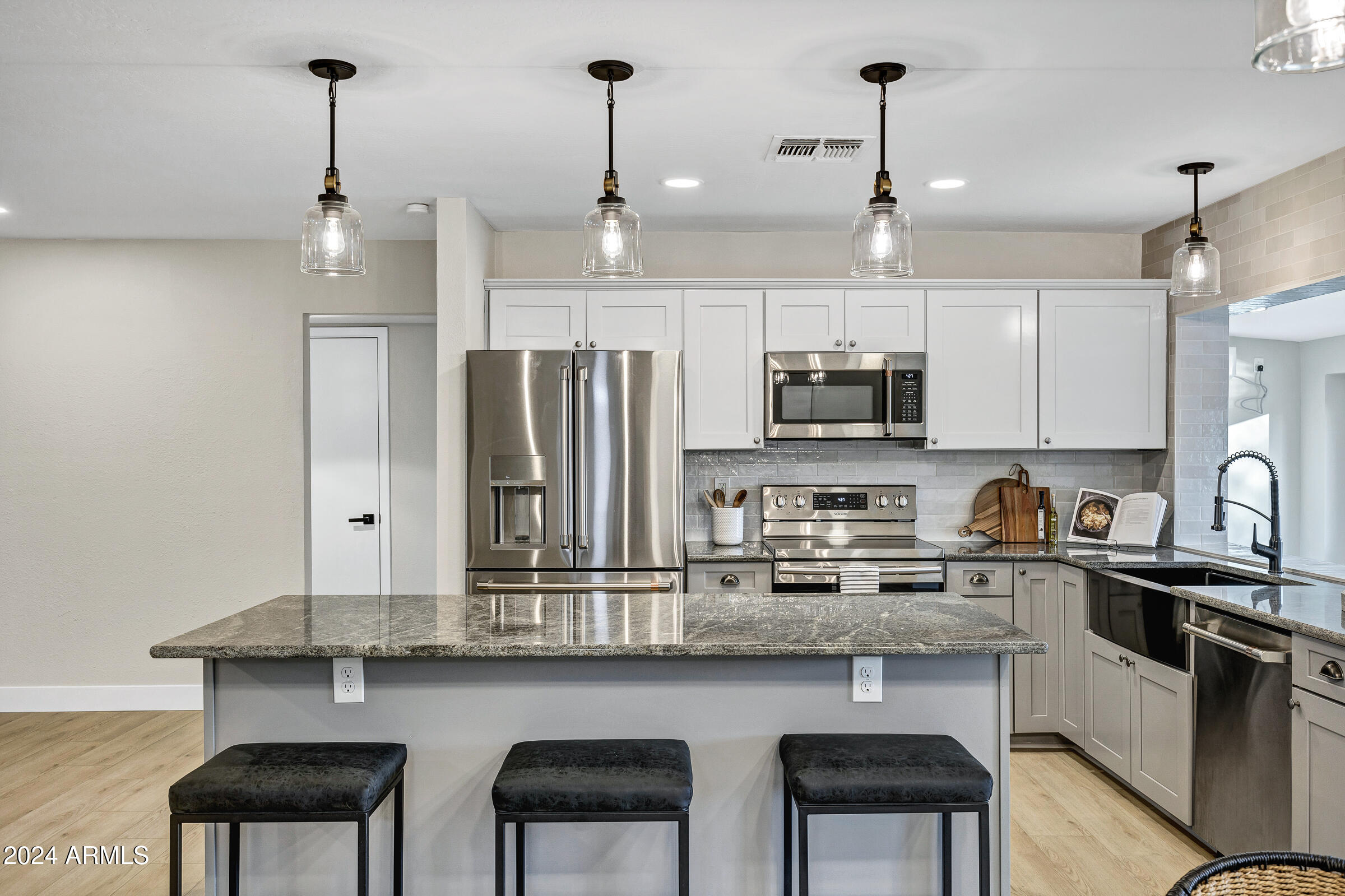 3701 West Phelps Road Phoenix, AZ 85053 - Photo 22 of 46 a kitchen with granite countertop a table chairs stove refrigerator and microwave