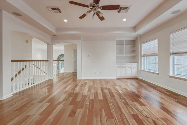 a view of empty room with wooden floor and fan