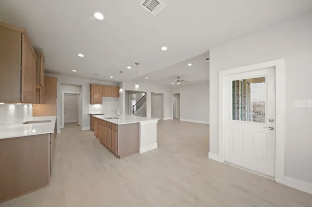 a large white kitchen with kitchen island a sink white cabinets and stainless steel appliances