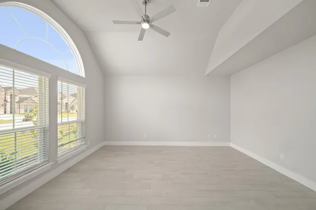 an empty room with windows and ceiling fan